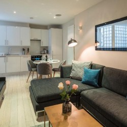 living area with console, TV, large sofa, dining table and kitchen, Goodge Street Apartments, Fitzrovia, London W1
