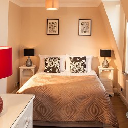 bedroom with double bed, side table and chest of drawers with large red lamp, hHammersmith Apartments, Hammersmith, London W6 Apartments, Hammersmith, London W6