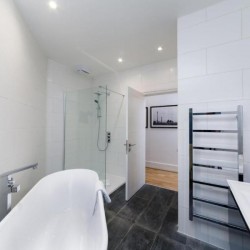 bathroom with shower, free standing bath tub and towel rail, living room with sofa, glass table, tv, chair and dining area, Garrick Charring Cross, Covent Garden, London WC2