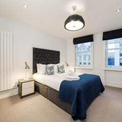 double bedroom with bed, towels and side tables, living room with sofa, glass table, tv, chair and dining area, Garrick Charring Cross, Covent Garden, London WC2