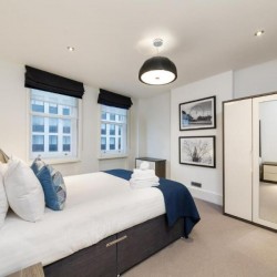 bedroom with double bed, large wardrobe and wall prints, living room with sofa, glass table, tv, chair and dining area, Garrick Charring Cross, Covent Garden, London WC2