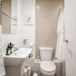 bathroom with towel rail, sink, toilet and bathrobes, Buckingham Apartments, Victoria, London SW1