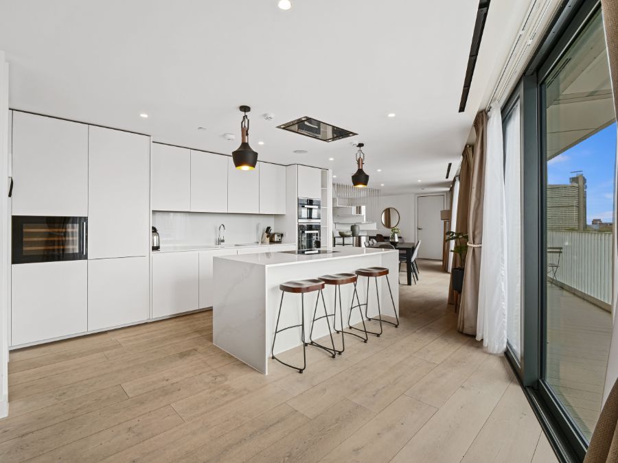 large white kitchen with breakfast bar, stools and view to dining area, 3 bedroom penthouse apartment