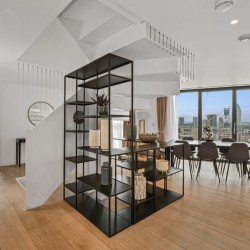 penthouse living room with large shelf rack, dining area, stairway to rooftop and view to the city of London, 3 bedroom penthouse apartment