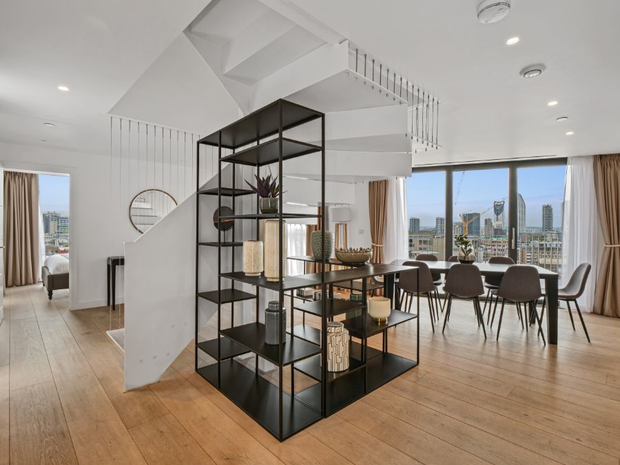 penthouse living room with large shelf rack, dining area, stairway to rooftop and view to the city of London, 3 bedroom penthouse apartment