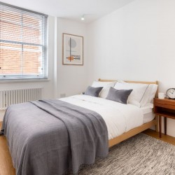 king size bed and side table with clock, Mar Apartments, Marylebone, London W1