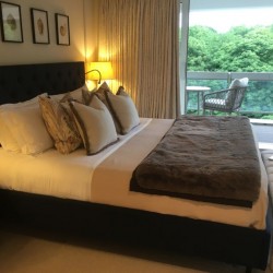 king size bed with several pillows and balcony with chair and table overlooking Hyde Park, Hyde Park Penthouse, Kensington, London SW7