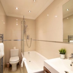 modern bathroom with towel rail, WC, bathtub, sink and mirror, The Executive Apartments, Kensington, London W8