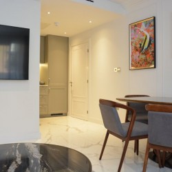 smart tv on wall, dining table, works of art and view to kitchen, St Johns Apartments, St Johns Wood, London NW8