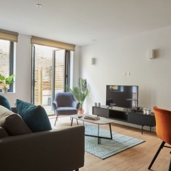 flat 9, living area with sofa, chair, console with TV, dining area and view to terrace, The Mews Homes, Hammersmith, London W6