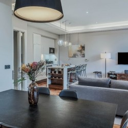 large dining table with flowers, sofa, breakfast bar in kitchen and TV, Chancery Lane Apartments, Holborn, London W1C