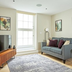 living room with sofa, cushions, grey rug, TV on stand and art on the walls, 1 bedroom apartment