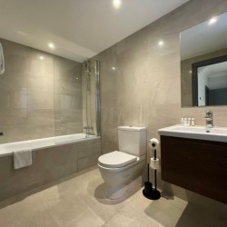 bathroom with bathtub, WC, paper holder, sink, mirror in Barons Court Apartments, Hammersmith, London W6