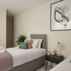 twin beds with cushions and towels. wall print, Munster Apartments, Fulham, London SW6
