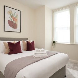 double bed with cushions, towels, plant, wardrobe and wall print, Munster Apartments, Fulham, London SW6