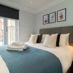 bedroom with king size bed, cushions and towels, Barons Court Apartments, Hammersmith, London W6